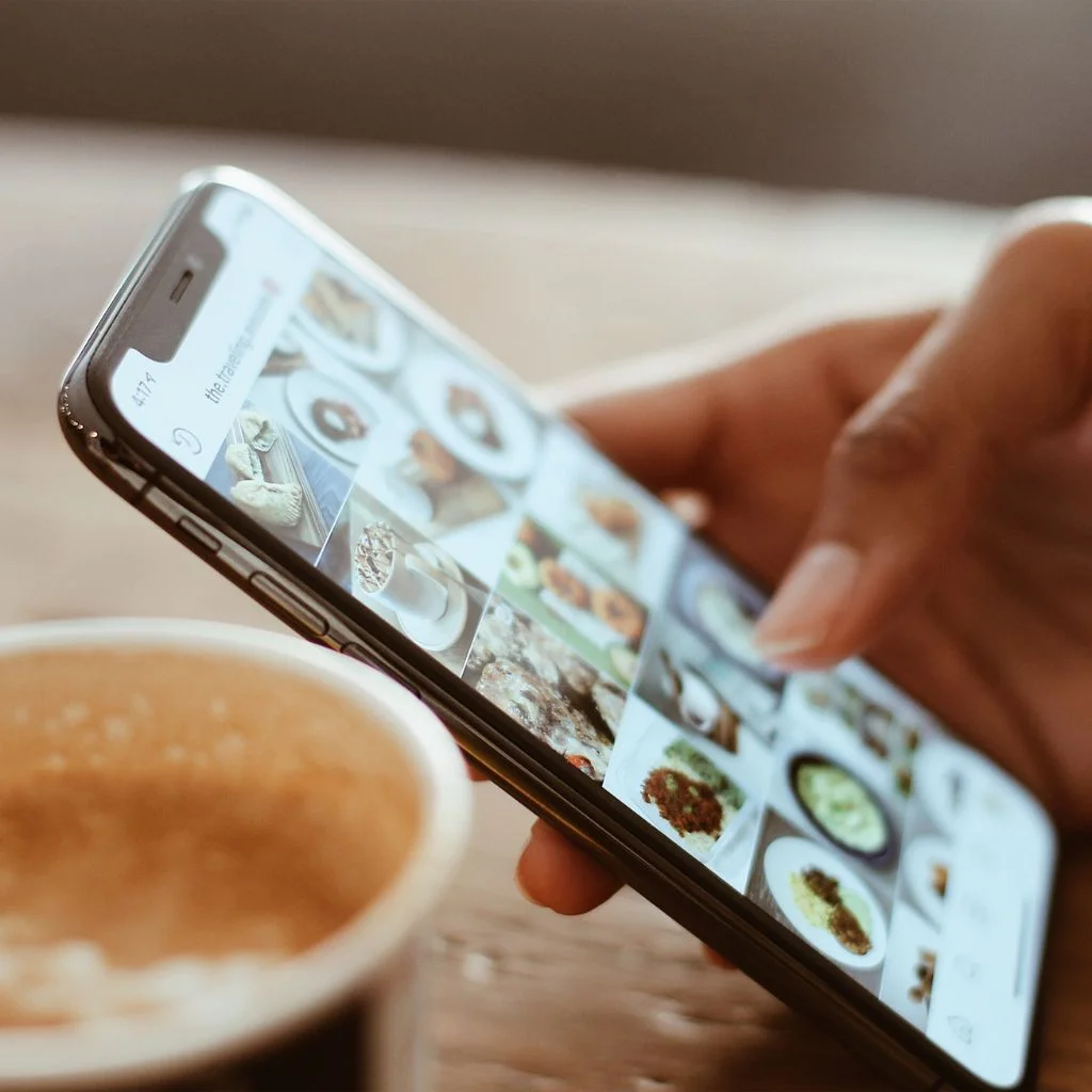 a-person-using-an-iphone-and-a-cup-of-coffee-on-a-wooden-table