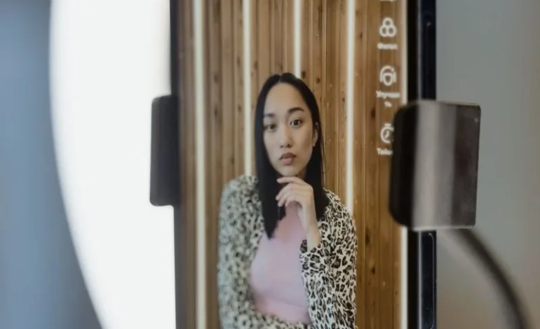 a woman taking a selfie with her phone in front of a ring light